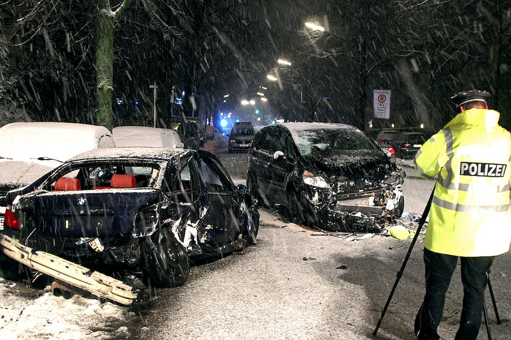 Ein Polizeibeamter steht am 10.12.2012 in Hamburg nach einem Glätteunfall mit zwei Autos an der Unfallstelle
