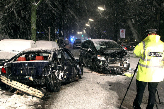 Ein Polizeibeamter steht am 10.12.2012 in Hamburg nach einem Glätteunfall mit zwei Autos an der Unfallstelle 