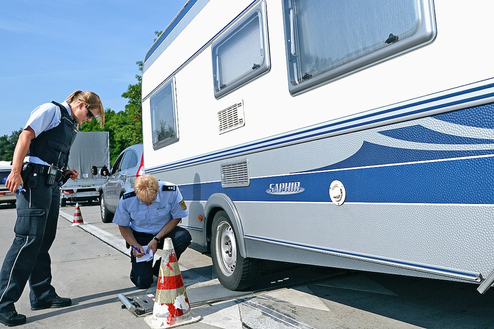 Zwei Polizeibeamte kontrollieren am 15.07.2013 an der A5 bei Neuenburg das Gewicht eines Wohnanhängers
