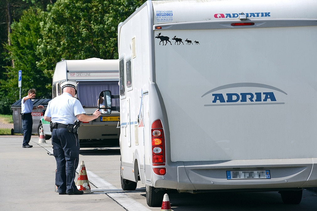 Zwei Polizeibeamte kontrollieren am 15.07.2013 an der A5 bei Neuenburg Fahrzeuge mit Wohnanhängern