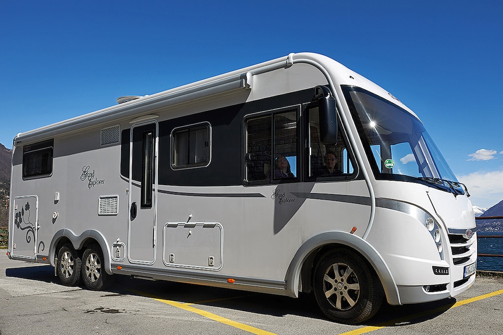 Ein Reisemobil vom Typ Grand Explorer des deutschen Herstellers LMC parkt am 04.04.2013 auf der Kuestenstrasse bei Brissago (Schweiz) auf einer Parkbucht am Lago Maggiore. Im Hintergrund die Alpen.