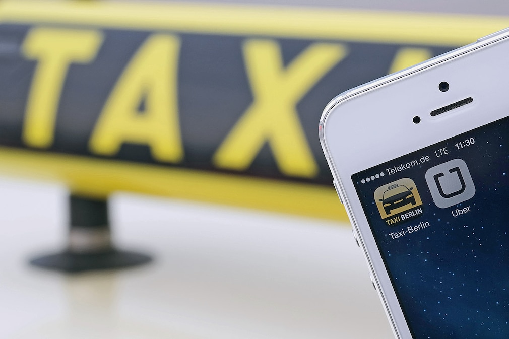 Die Handy-Apps "Uber" und "Taxi Berlin" sind am 11.06.2014 auf einem Smartphone vor einem Taxi in Berlin zu sehen