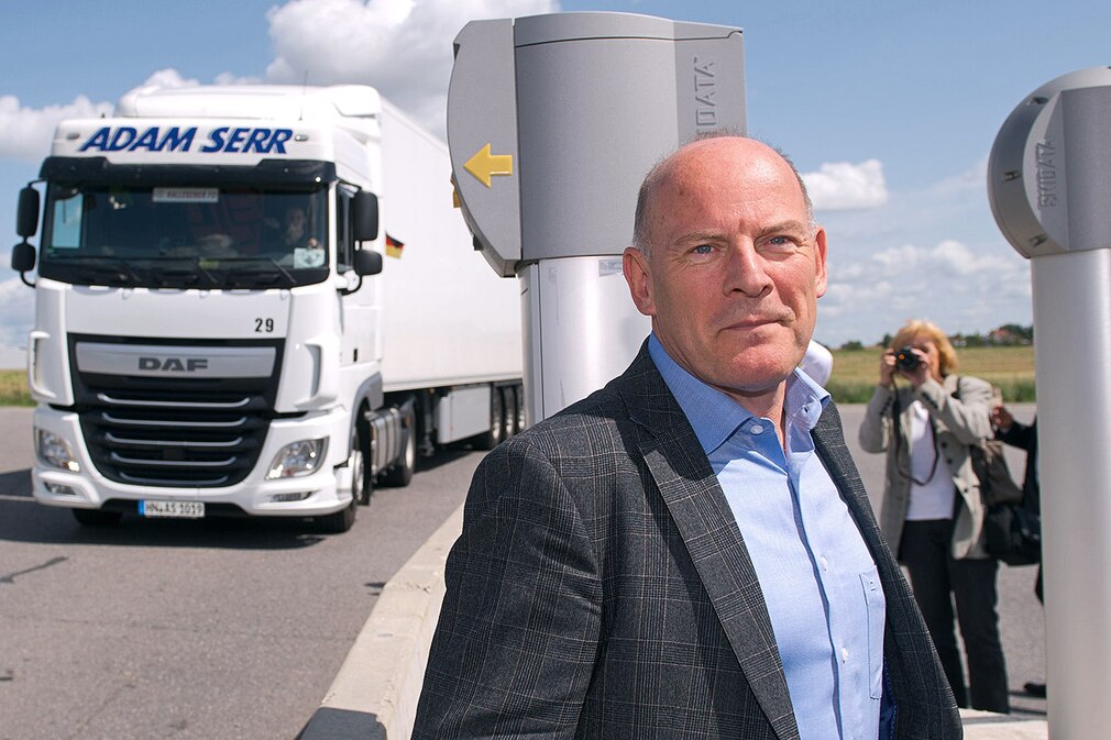 Der baden-württembergische Verkehrsminister Winfried Hermann (Bündnis 90/Die Grünen) steht am 11.08.2014 bei der Vorstellung des telematischen LKW-Parkens auf einem Autohof bei Bad Rappenau an einer Parkplatzeinfahrt neben einem LKW