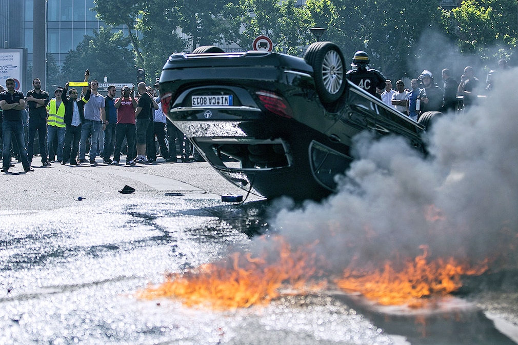 An UberPop vehicle overturned by French taxi drivers as they clash with riot police, during a demonstration against the app-based transportation network and taxi company Uber's UberPop service in Paris