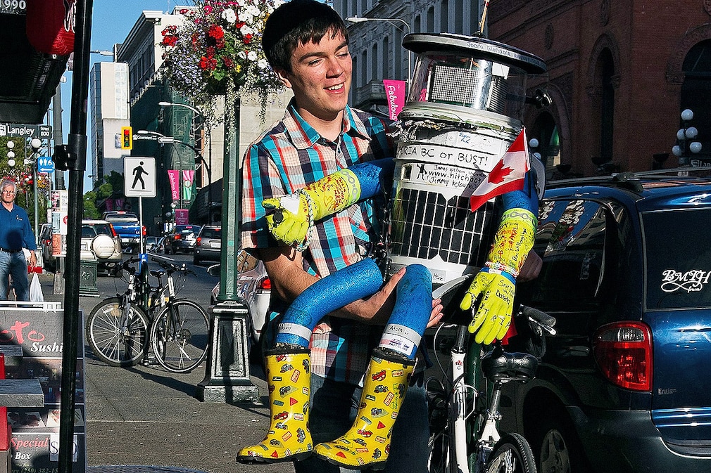 Colin Gagich, a developer of Hitchbot, checks out the robot while it sits on a chair in the Inner Habour in Victoria, Vancouver Island, British Columbia, Canada, 21 August 2014