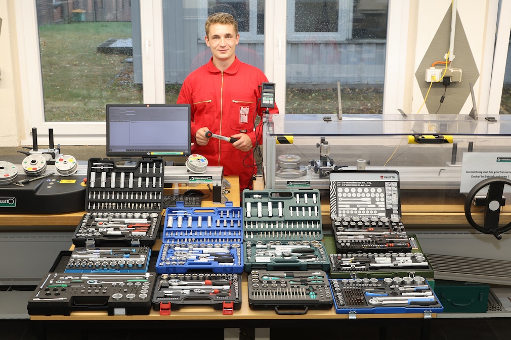 Werkstattsituation: Eine Person steht hinter einem Werktisch, auf dem einige Steckschlüssel-Set-Kästen liegen.