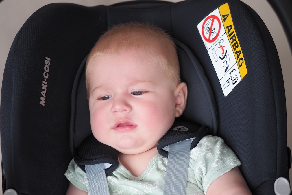 Ausschnitt einer Babyschale mit Baby, der zeigt, dass die Kopfstütze zu breit ist und zu viel Spiel zwischen Kopf und Stützen besteht.