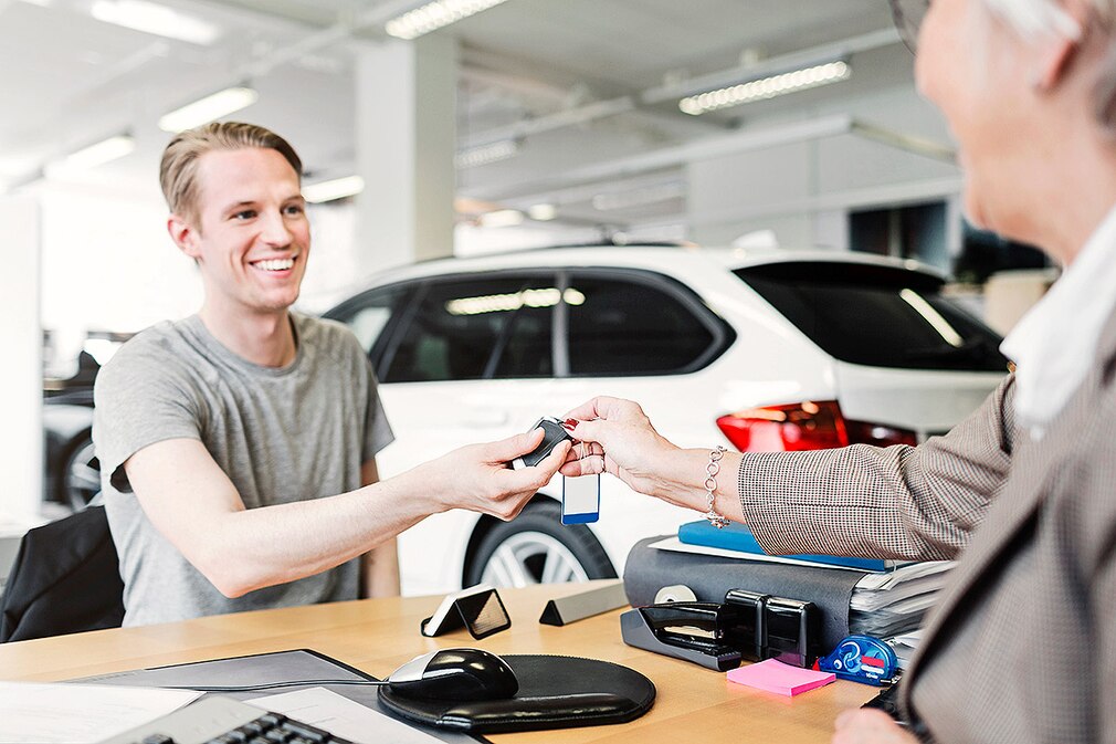 Mann bekommt seine neuen Autoschlüssel überreicht