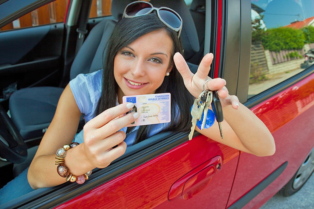Frau mit neuem Auto und Führerschein und Autoschlüssel