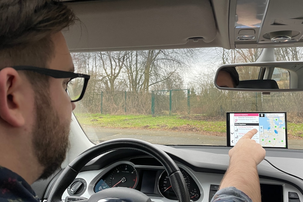 Navi-Person sitzt in einem Fahrzeug und bedient ein an der Frontscheibe befestigtes Navi von Garmin.