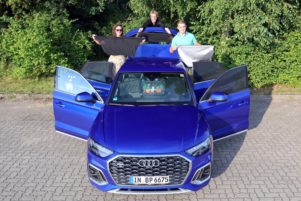 Ein Fahrzeug von vorn, in dem an jeder Scheibe Sonnenschutzsysteme befestigt sind. Ums Heck herum stehen drei Personen und halten weitere Systeme in der Hand.