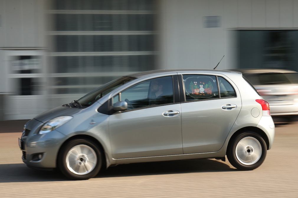 Seitenansicht eines vorbeifahrenden Kleinwagen mit Sonnenschutzsystem im hinteren Türfenster.