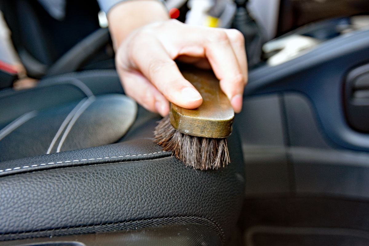 Verfahren zur reinigung von ledersitzen mit schaum und reinigungsmitteln  mit einer bürste arbeiter im autoreinigungsdienst reinigen das auto im  innenraum detaillierung des autoinnenraums