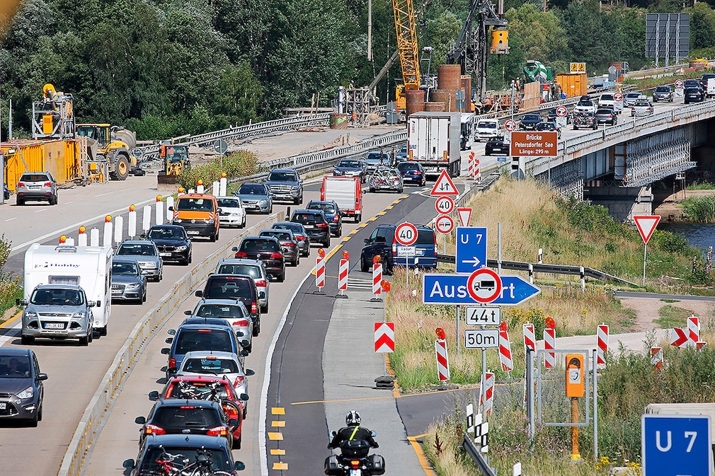 Traffic is backed up at the Petersdorfer Bridge construction site of the A19 Berlin-Rostock near Malchow (Mecklenburg-Western Pomerania), 22 July 2016, while the foundations for the new bridge are being built in the background. Traffic jams are inevitable during the holiday season: up to 38,000 vehicles are on the main travel days on the A19, but a two-lane road can only handle up to 25,000. The first new bridge should be ready in May 2017 and open to traffic with four lanes.