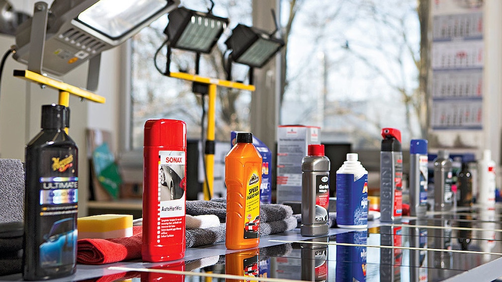 Laborsituation: Perspektive auf eine Reihe von Autowachs-Produkten, stehend auf den dazugehörigen, hart beleuchteten Testfeldern.