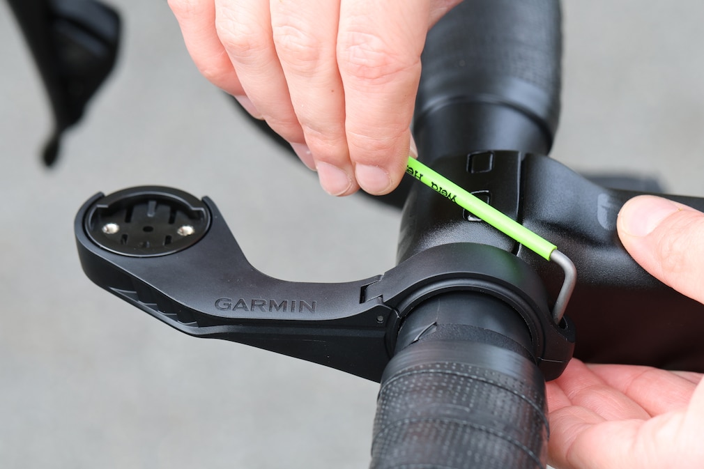 Nahaufnahme einer Hand beim Befestigen einer Fahrradcomputerhalterung mit einem Inbusschlüssel.