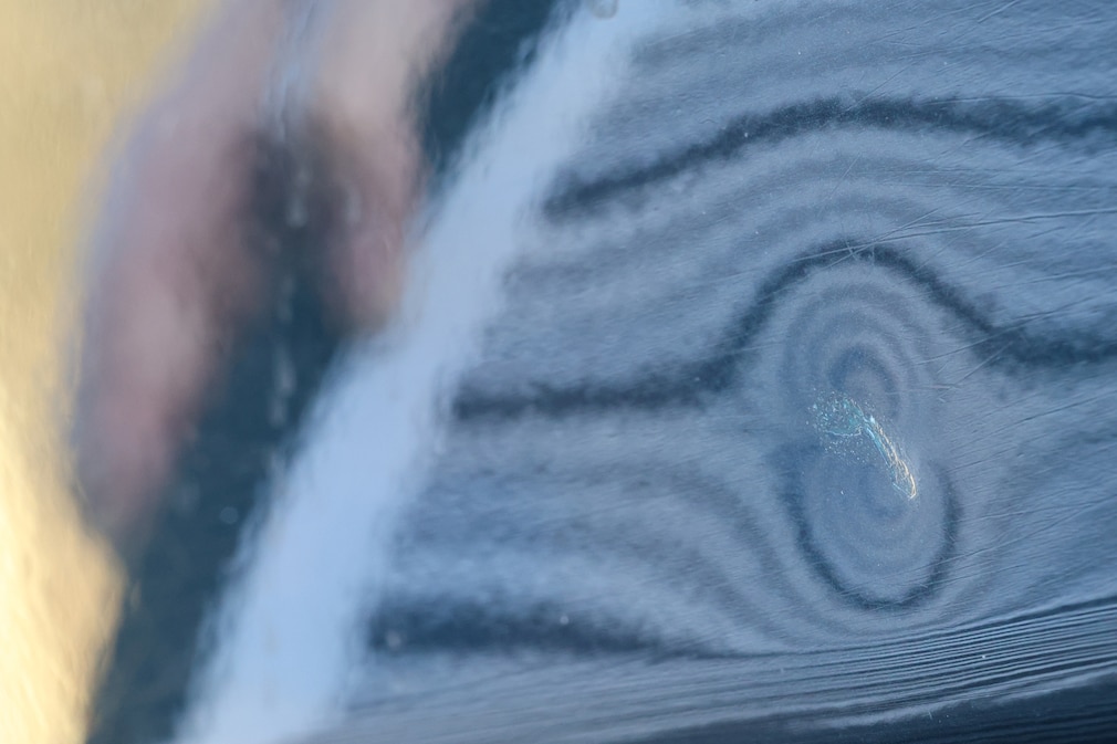 Ansicht einer Delle im Lack einer Karosserie, sichtbar gemacht mit einem Reflektorboard.