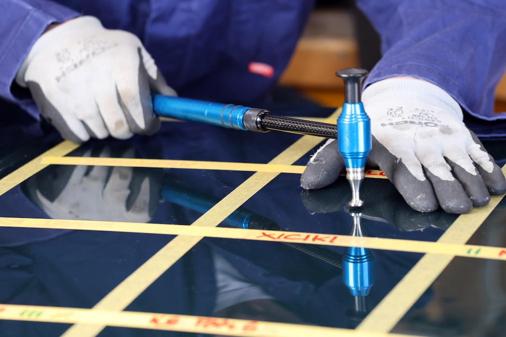 Person arbeitet mit Ausbeul-Hammer an einer Beule im Testfeld.