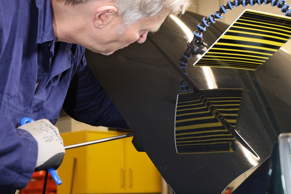 Person arbeitet mit einem Dellenhebelwerkzeug an einer Motorhaube.
