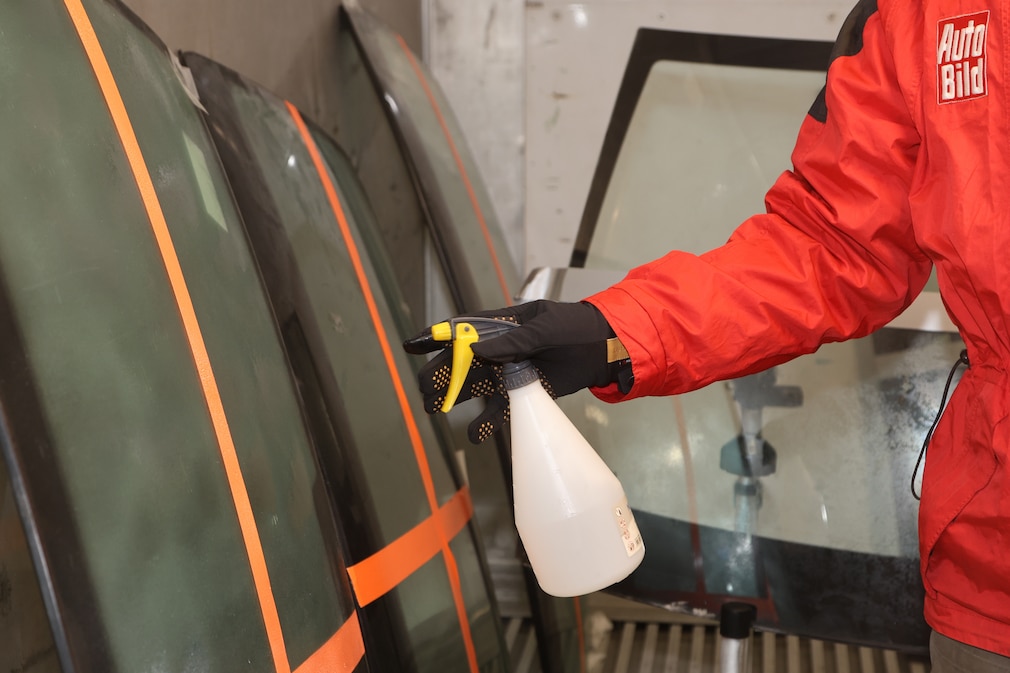 Mittels Pumpsprühflasche wird eine Eisschicht auf die gefrorene Frontscheibe aufgebracht