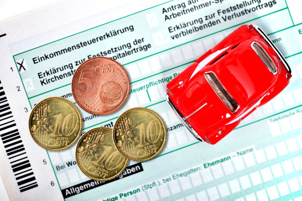 Miniaturauto auf Einkommensteuererklärung mit Geldmünzen Miniaturauto auf Einkommensteuererklärung mit Geldmünzen