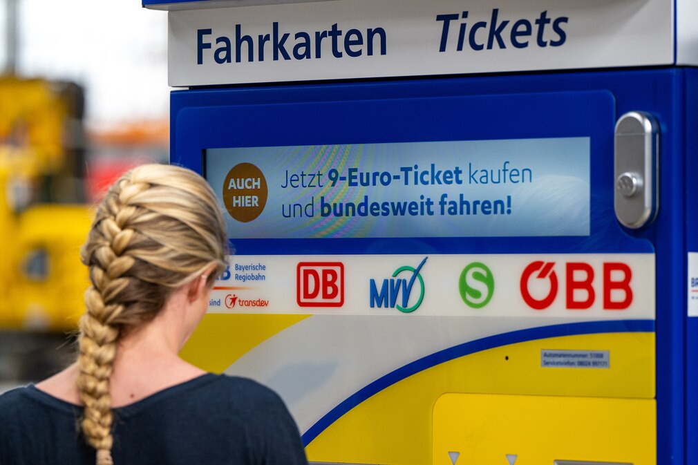 Frau am Bahnfahrkartenautomat mit Hinweis auf 9-Euro-Ticket Frau am Bahnfahrkartenautomat mit Hinweis auf 9-Euro-Ticket
