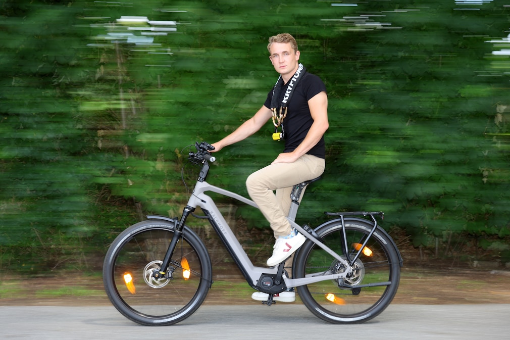 Seitenansicht eines Fahrradfahrers in Vorbeifahrt mit Kettenschloss um den Hals