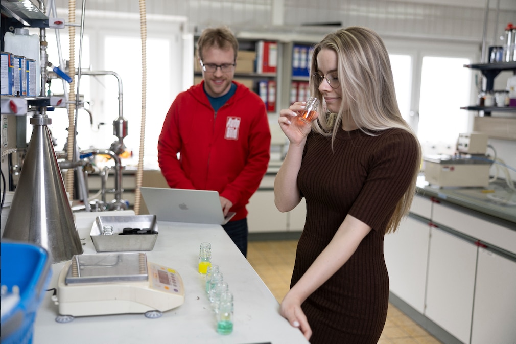 Frau riecht an Glas mit Flüssigkeit