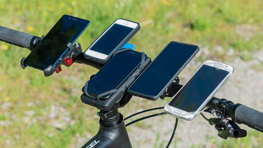 Perspektive eines graden Fahrradlenkers, bestückt mit fünf Handyhalterungen und Smartphones