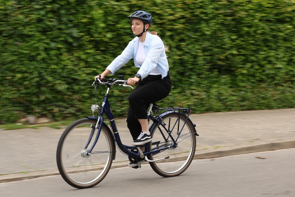 Vorbeifahrt einer Person auf einem Fahrrad schräg von vorn. Am Lenker sind verschiedene Tachos montiert.