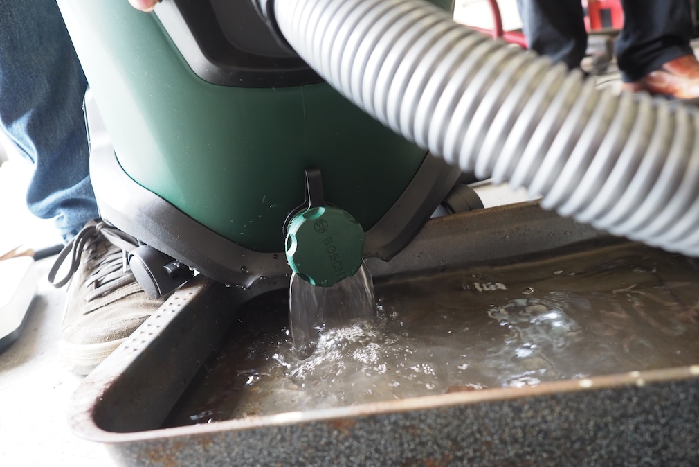 Nahaufnahme: Bosch Staubsauger mit geöffneter Ablassschraube über Auffangbecken.