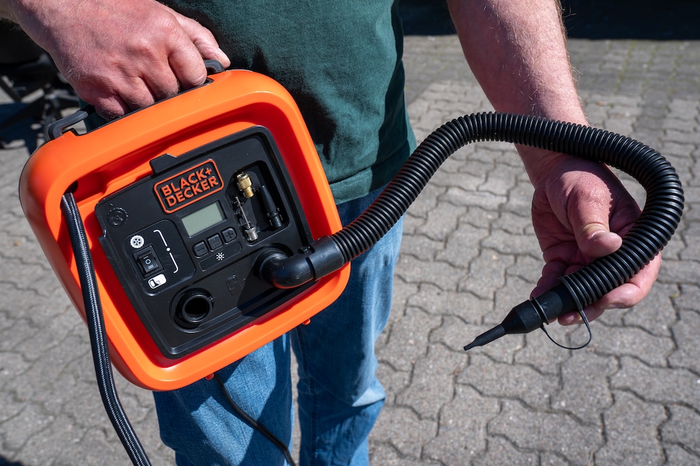 Produktfoto eines Black and Decker-Kompressors, in der Hand wird ein Niedrigdruckschlauch gehalten.