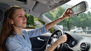Autofahrerin in Berlin richtet ihren Rückspiegel