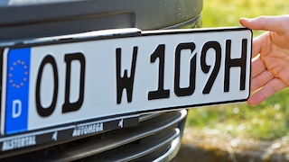 Hand bringt H-Kennzeichen an,