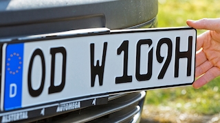 Hand bringt H-Kennzeichen an,