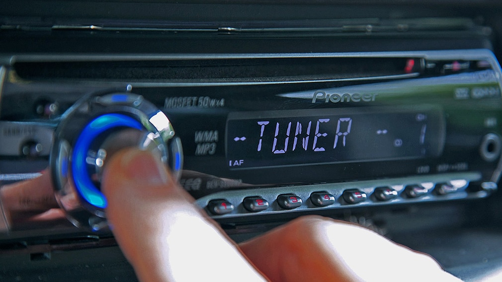 Ein Mann sucht einen neuen Sender an seinem Autoradio