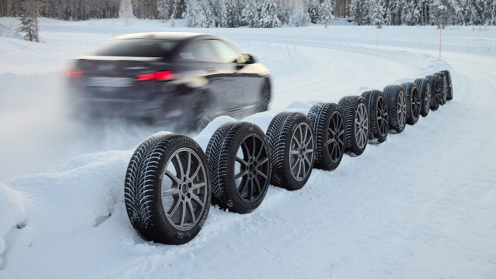 BMW fährt an aufgereihten Winterreifen vorbei