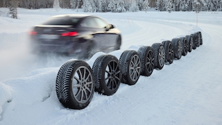 BMW fährt an aufgereihten Winterreifen vorbei