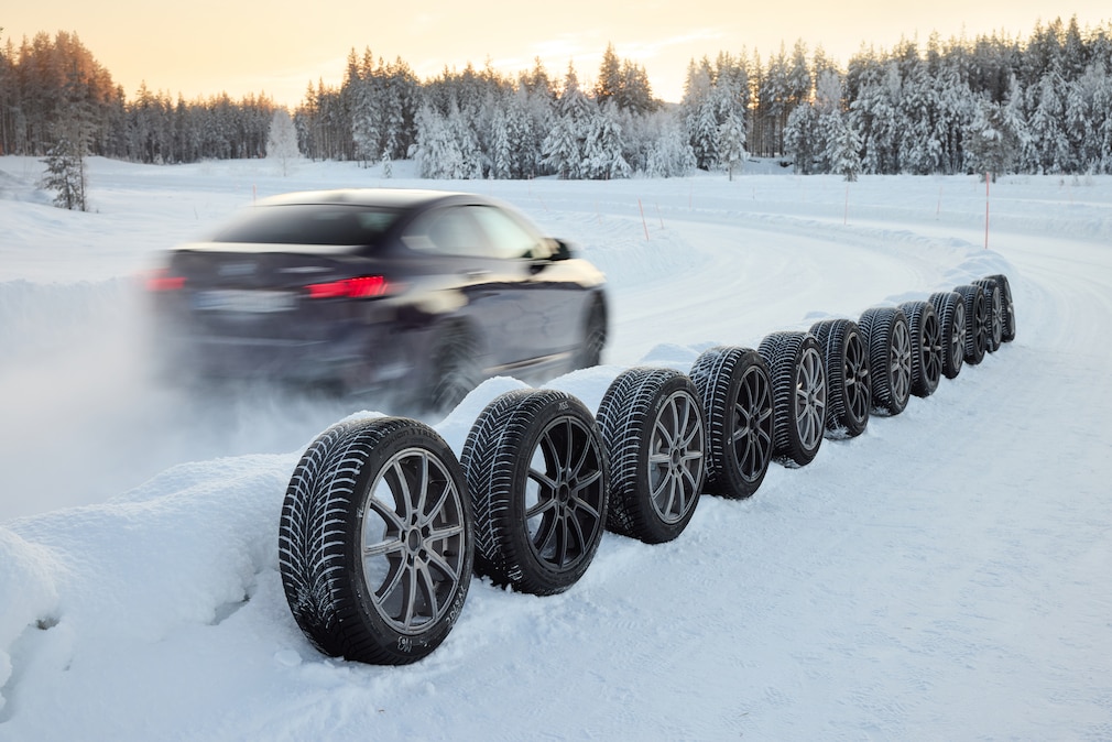 BMW fährt an aufgereihten Winterreifen vorbei