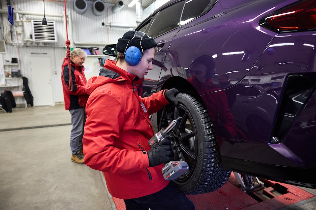 Zwei Redakteure in roter AUTO BILD Jacke montieren einen Reifen