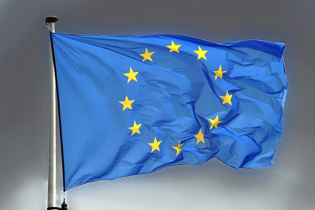 Wehende Europa-Flagge vor bedrohlich-grauem Hintergrund.