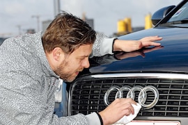 Mann poliert Kühlergrill mit Audi-Emblem