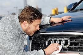Mann poliert Kühlergrill mit Audi-Emblem