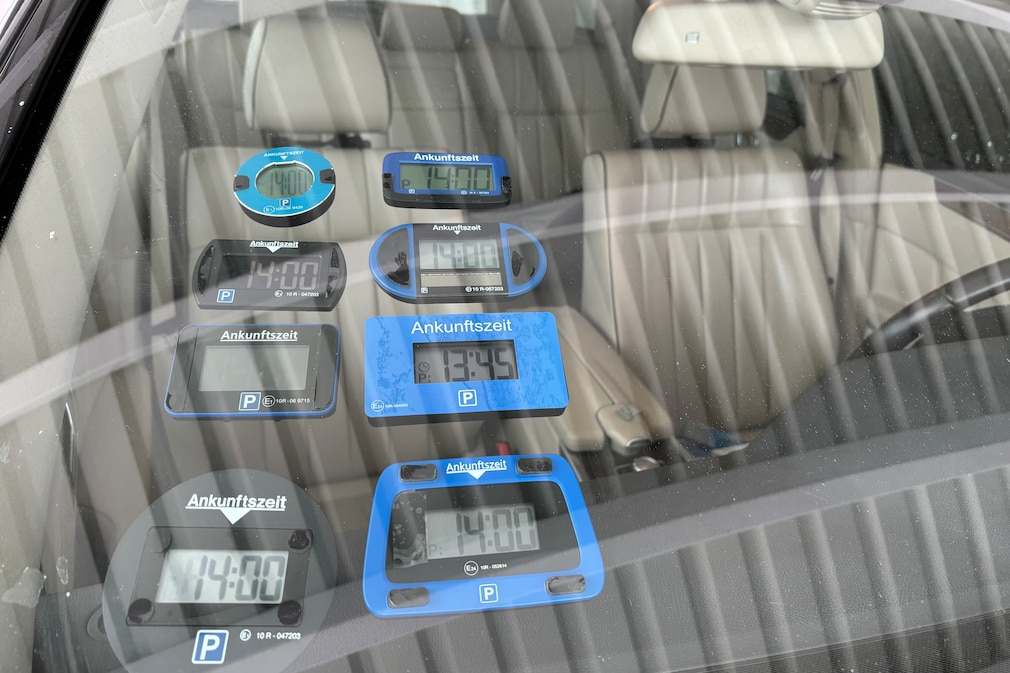 Nahaufnahme: An einer Frontscheibe sind elektronische Parkscheiben angebracht.