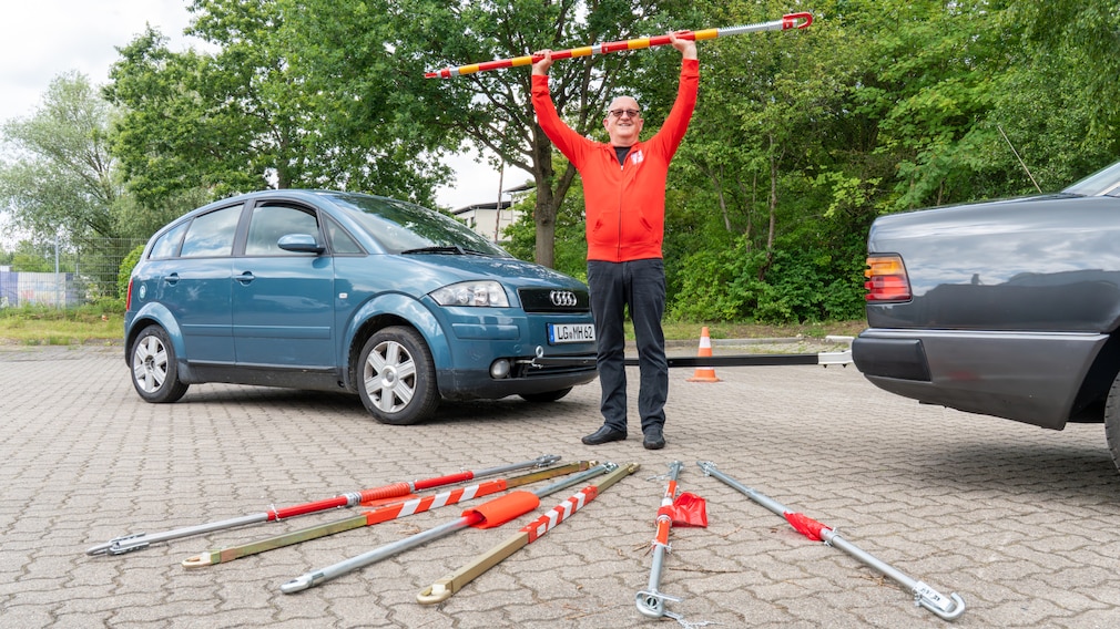 Redakteur auf Aufmacherbild mit allen Abschleppstangen vor zwei Autos positiioniert.