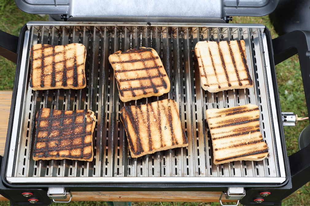 6 unterschiedlich gebräunte Toasts liegen auf der Grillfläche eines Geräts.