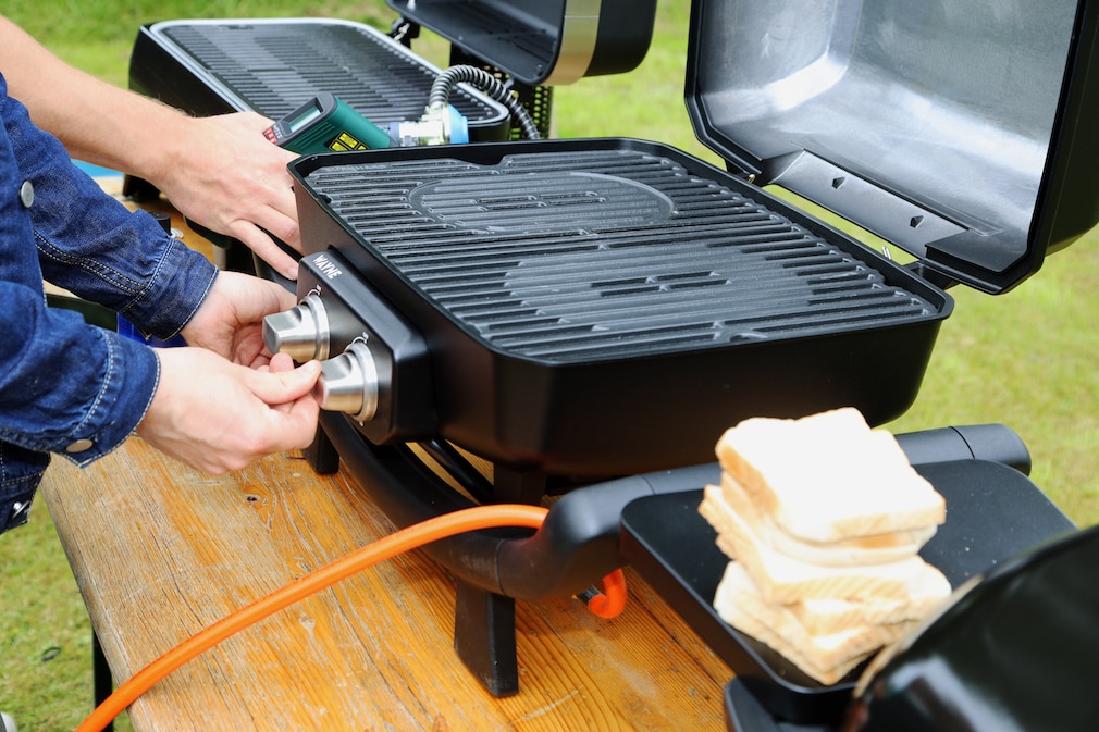 Gasgrill beim Aufheizen im Anschnitt: Vorbereitung für den Toasttest. Einige Toasts liegen gut sichtbar im Vordergrund.
