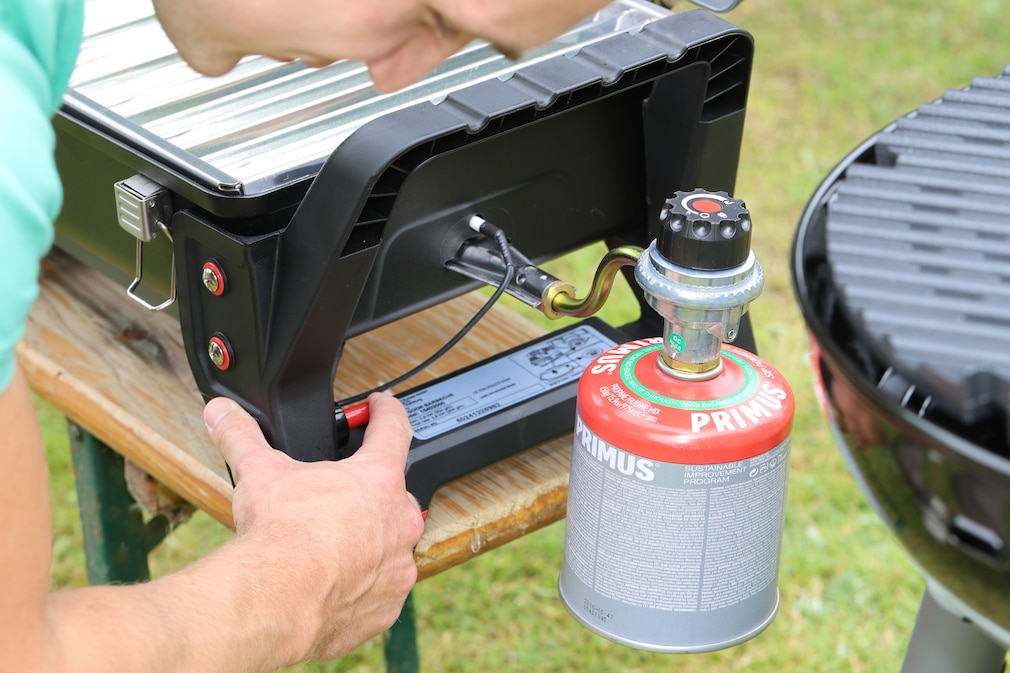 Nahaufnahme: eine Person betätigt den Auslöser einer Piezo-Zündung an einem Camping-Gasgrill.
