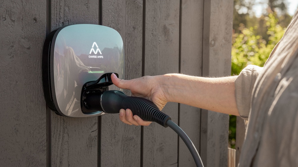 Person steckt Ladekabel in Wallbox