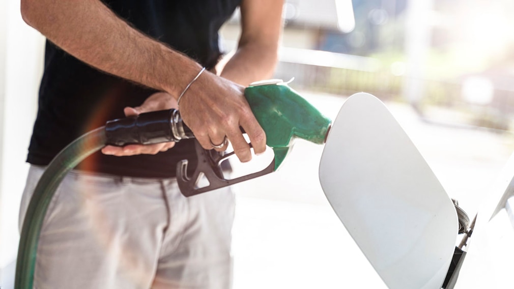 Ein Mann Tankt sein Auto an einer Zapfsäule an einer Tankstelle - Symbolbild Tanken